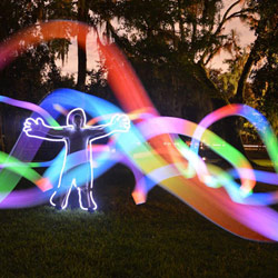 a figure stands in the dark with light streaks surrounding them